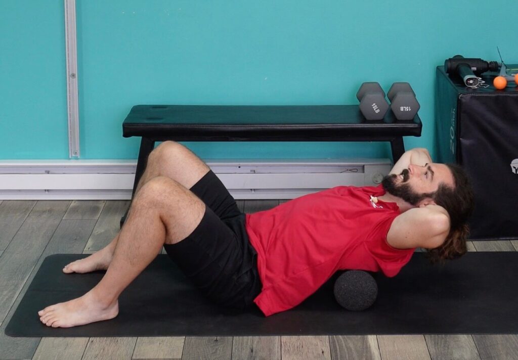 Dr. John laying with a circular foam roller in the mid back for back pain relief